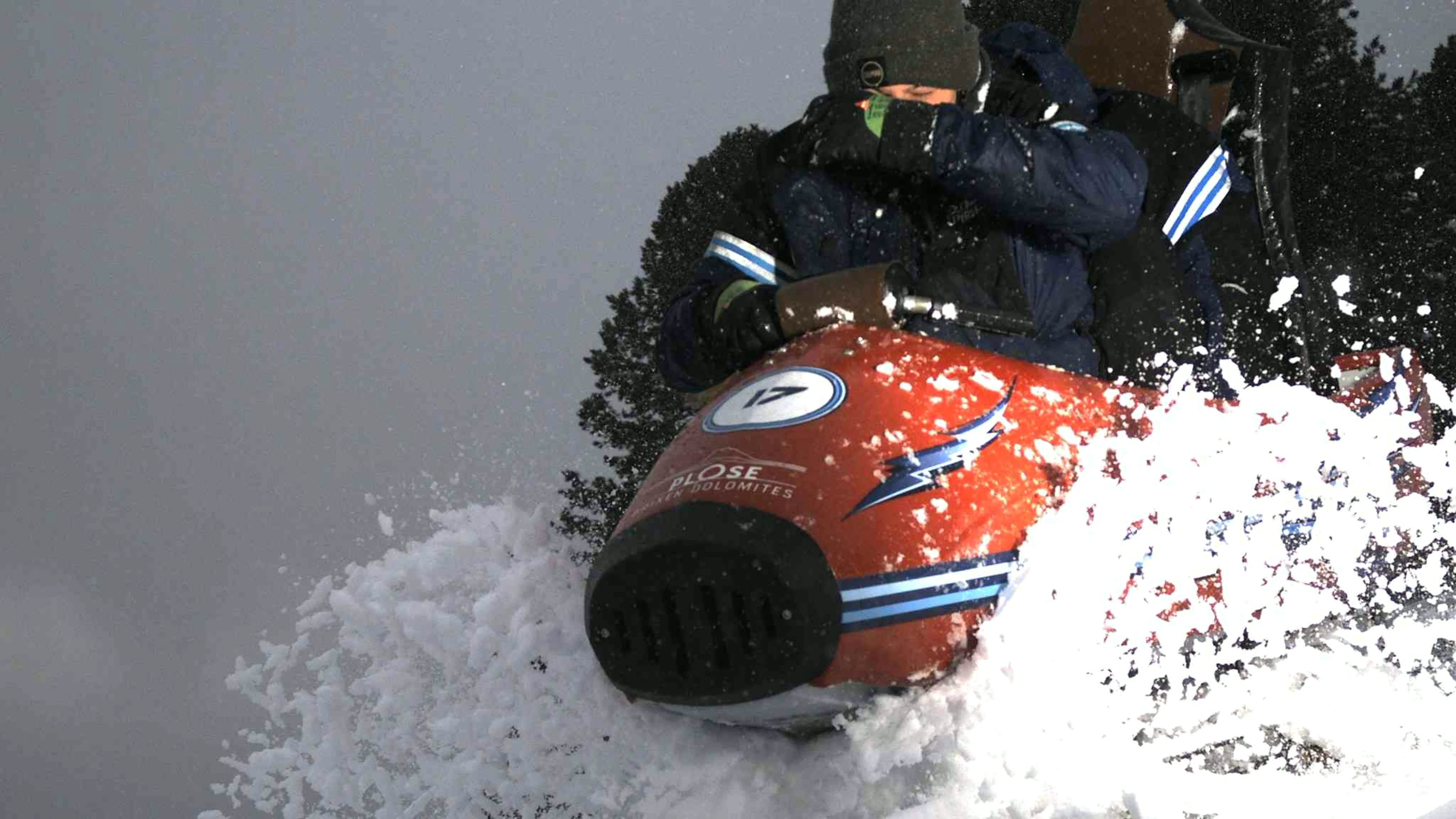 Winterrodelbahn mit mehreren Fahrgaesten auf einer alpinen Schneeattraktion